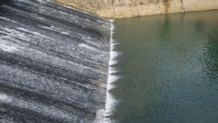 water flowing from dam into the river - obrazy, fototapety, plakaty