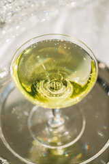 chartreuse green cocktail in coupe glass with sparkling silver background