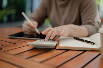 A close-up shot of a woman using a calculator, calculating her salary and monthly expenses.