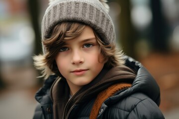Portrait of a boy in a warm hat and coat. Outdoors.