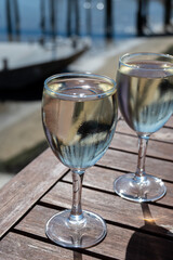 Drinking of white wine at farm cafe in oyster-farming village, with view on boats and water of...