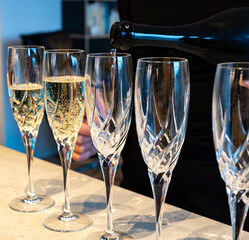 Birthday party, pouring of brut champagne bubbles cava or prosecco wine in tulip glasses with kitchen on background