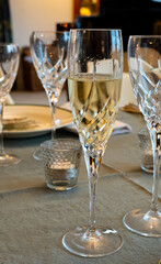 Birthday party, pouring of brut champagne bubbles cava or prosecco wine in tulip glasses with kitchen on background