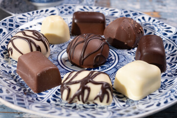 Variety of luxury belgian chocolate pralines bonbons on blue china porcelain plate, tea time