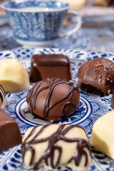 Variety of luxury belgian chocolate pralines bonbons on blue china porcelain plate, tea time