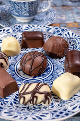 Variety of luxury belgian chocolate pralines bonbons on blue china porcelain plate, tea time