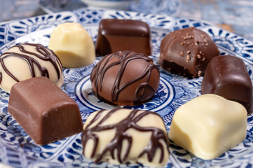 Variety of luxury belgian chocolate pralines bonbons on blue china porcelain plate, tea time