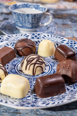 Variety of luxury belgian chocolate pralines bonbons on blue china porcelain plate, tea time