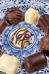 Variety of luxury belgian chocolate pralines bonbons on blue china porcelain plate, tea time