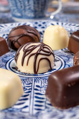 Variety of luxury belgian chocolate pralines bonbons on blue china porcelain plate, tea time
