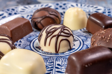 Variety of luxury belgian chocolate pralines bonbons on blue china porcelain plate, tea time