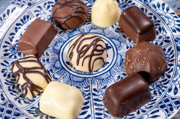 Variety of luxury belgian chocolate pralines bonbons on blue china porcelain plate, tea time