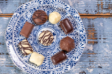 Variety of luxury belgian chocolate pralines bonbons on blue china porcelain plate, tea time