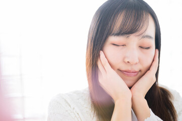 若い女性の顔に手を添えるビューティーや恋愛などのイメージ　目を閉じる　左にコピースペースあり