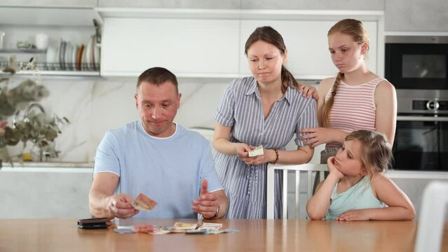 Dissatisfied husband and father give out pocket money to wife and children in home kitchen. High quality 4k footage