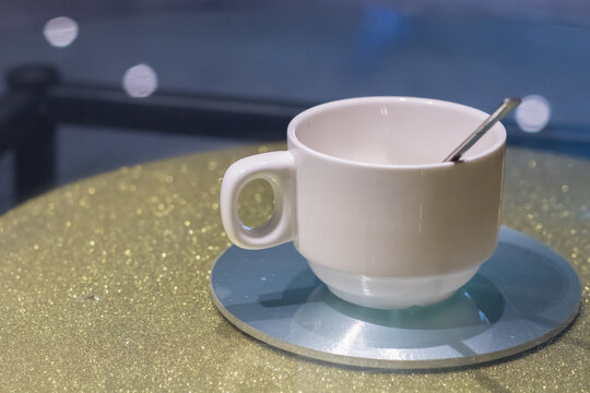 A white ceramic coffee cup mug is placed on a table top.