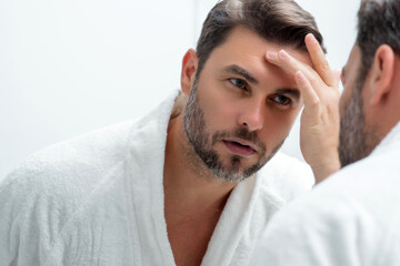 Attractive man with perfect skin touch face after shaving. Skin care healthcare cosmetic procedures...