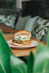 A close-up of a hamburger with toasted sesame seed bun, a beef patty, cheese, tomato, onion, lettuce, ketchup, and mustard