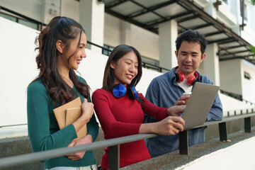 Group of Asian university students with headphones studying outdoor learning Make data reports from...