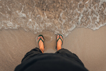 waves and naked feet on a sand beach in evening