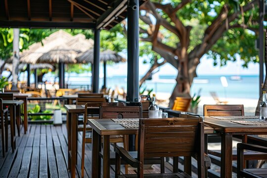 Caf terrace with wooden tables and chairs Providing a cozy outdoor setting for dining Against a backdrop of a blurred beach scene.