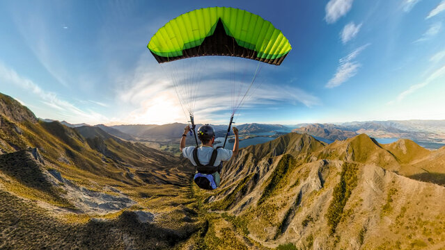 Extreme paraglider pilot flying over New Zealand mountains, adventure concept.