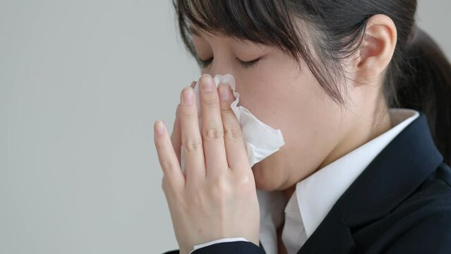 鼻水をティッシュでかむ花粉症の女性