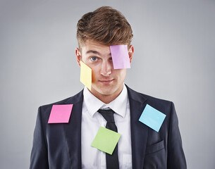Business man, overwhelmed and sticky note on face, suit or clothes in studio portrait by...