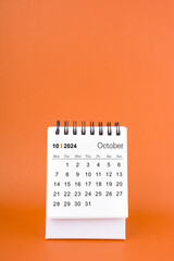 Vertical of October 2024 table calendar on orange background.