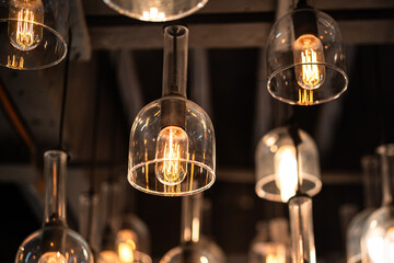 Classic sphere lighting bulbs are glowing in orange warming shade, there are hanging from ceiling in dark environment. Interior cozy style decoration. Close-up and selective focus.