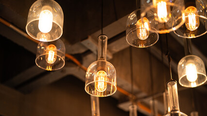 Classic sphere lighting bulbs are glowing in orange warming shade, there are hanging from ceiling...