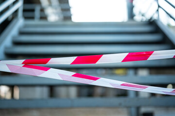 Close-up at the red-white barricade tape, using for secure the restricted area with background of banister route. 