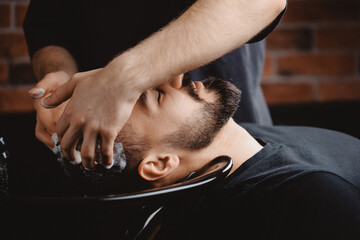 Hairdresser use shampoo for washing hair of man in barbershop. Concept spa cosmetic for men