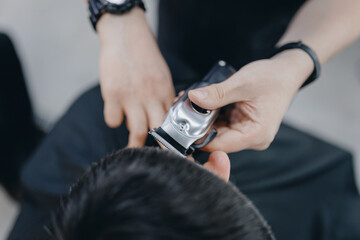 Closeup master barber hairdresser does hairstyle with hair clipper and comb. Concept banner...