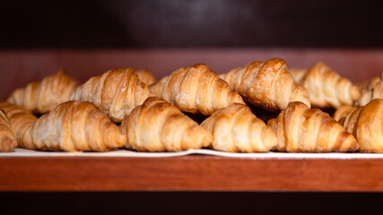 Group of baked croissants are placed on the shelf of the breakfast buffet meal. Bakery food object photo, selective focus. 