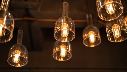 ceiling lighting bulbs are glowing in orange warming shade in dark environment. Interior cozy style decoration. Close-up and selective focus.