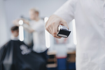 Barber shop banner. Closeup hairdresser holds hair clipper on barbershop background, with sunlight