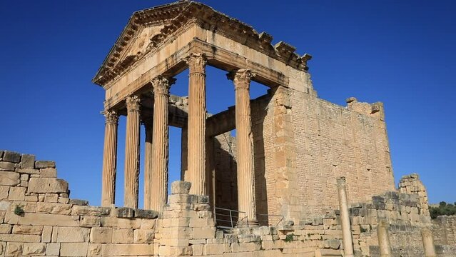 Clear blue sky over well-preserved Roman ruins at Dougga, ancient stone columns and architrave