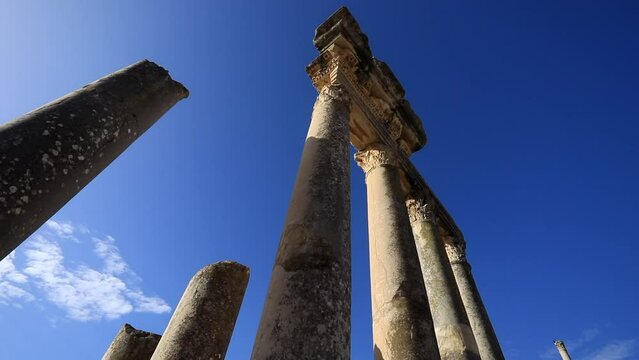 Low angle view of ancient Roman ruins against a clear blue sky in Dougga, Tunisia, sunlit