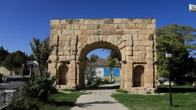 Sunny day showcasing the ancient Roman arch ruins at Dougga, clear blue sky background, static shot