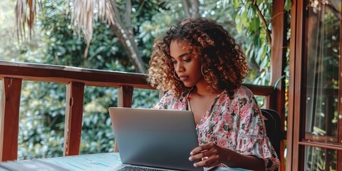 African American Woman using laptop to work from home (wfh) on her condo balcony - obrazy, fototapety, plakaty