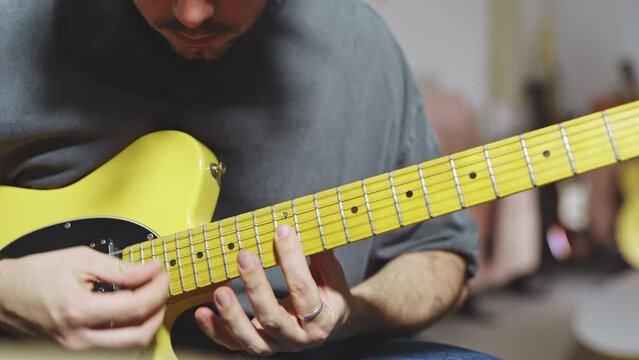 close up of skilled musician play Stratocaster yellow guitar in studio