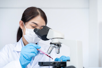 The female scientist is collecting a blood droplet to prepare for microscopic examination in the...
