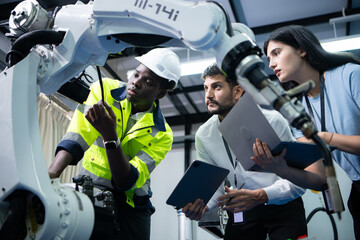 Technicians are introducing industrial hand robots to businessperson of factory industry who will...
