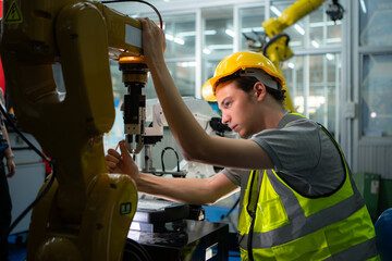 Technician who maintains a small robot arm the operation of a small robot arm used in industry is being repaired.