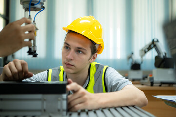 Portrait of a technician young male worker in a factory working on a small robot machine