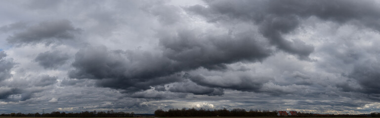 Panoramafoto einer geschlossenen, grauen Wolkendecke mit Gewitter- und Haufenwolken in Unteransicht - obrazy, fototapety, plakaty