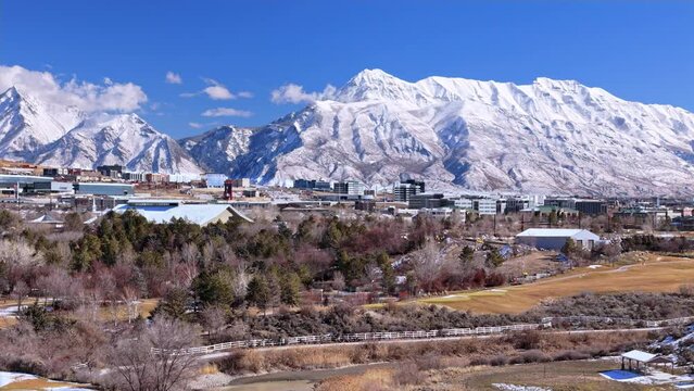 Bright sunny day across the Thanksgiving Point area overlooking Silicon Slopes in Lehi, Utah with majestic mountains behind. Moving left.