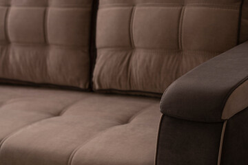 Quilted brown sofa with stitched velor cushions. Upholstered furniture with an armrest made of a...