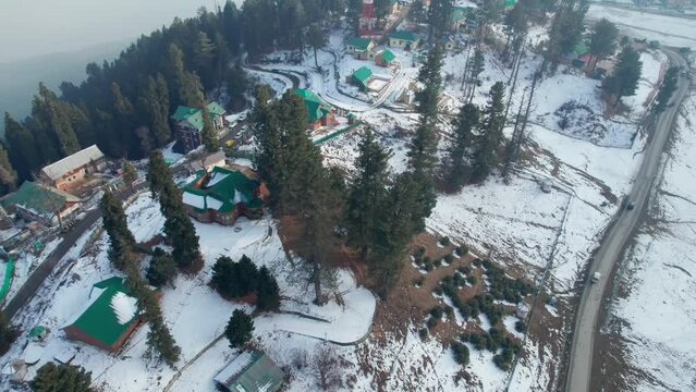 beautiful aerial view of gulmarg with houses, trees and snow in winter, drone pan shot, jammu and kashmir, india